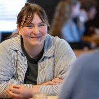Guest sitting at table, smiling at person across from her